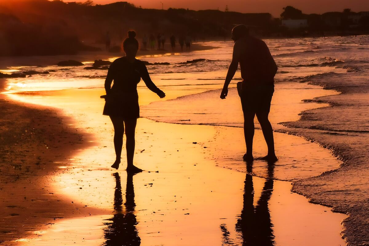 Couple marchant sur la plage au coucher du soleil